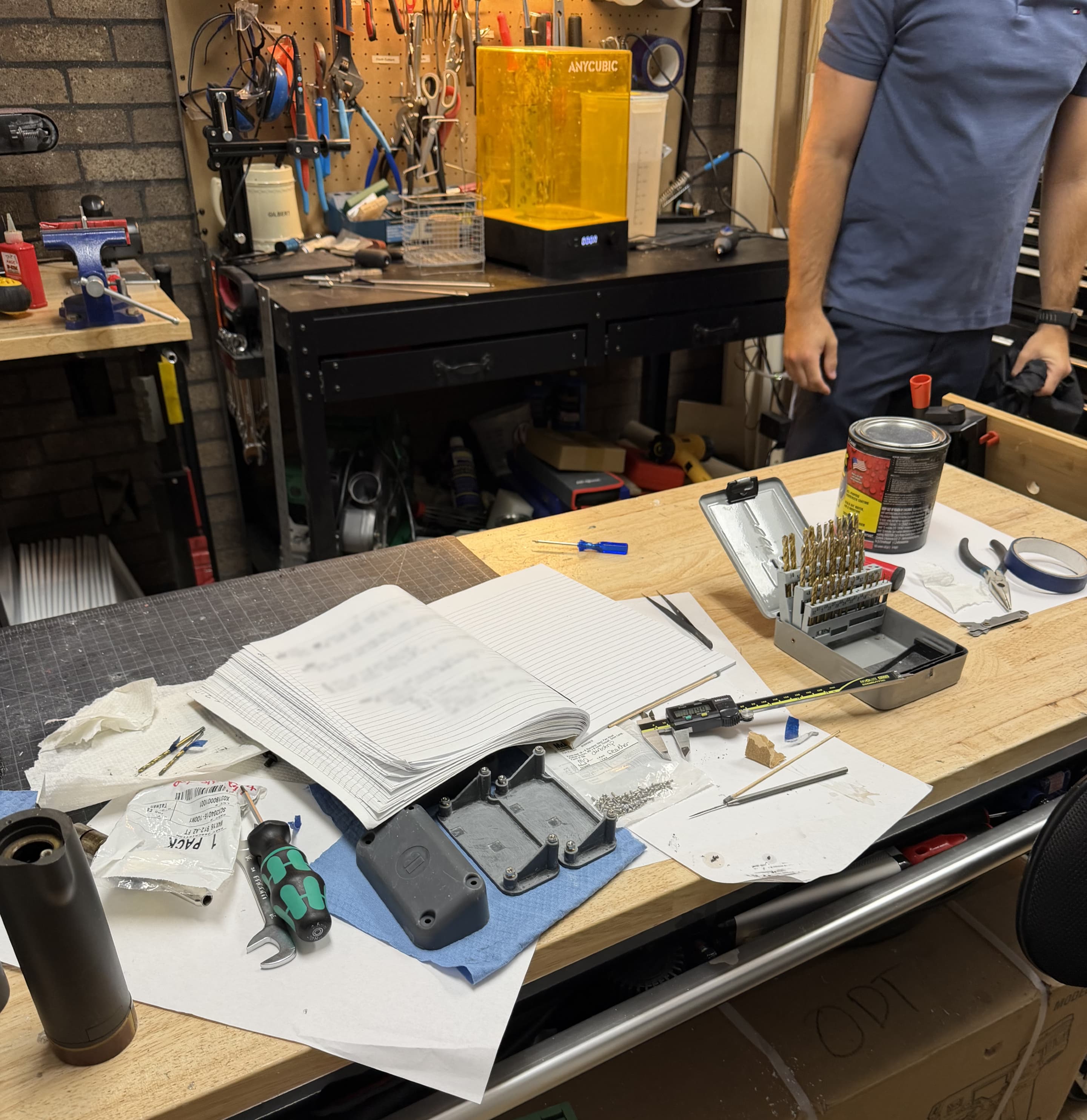Bizzi sensor housings, calipers, tools and an engineering notebook on a product-development workbench.