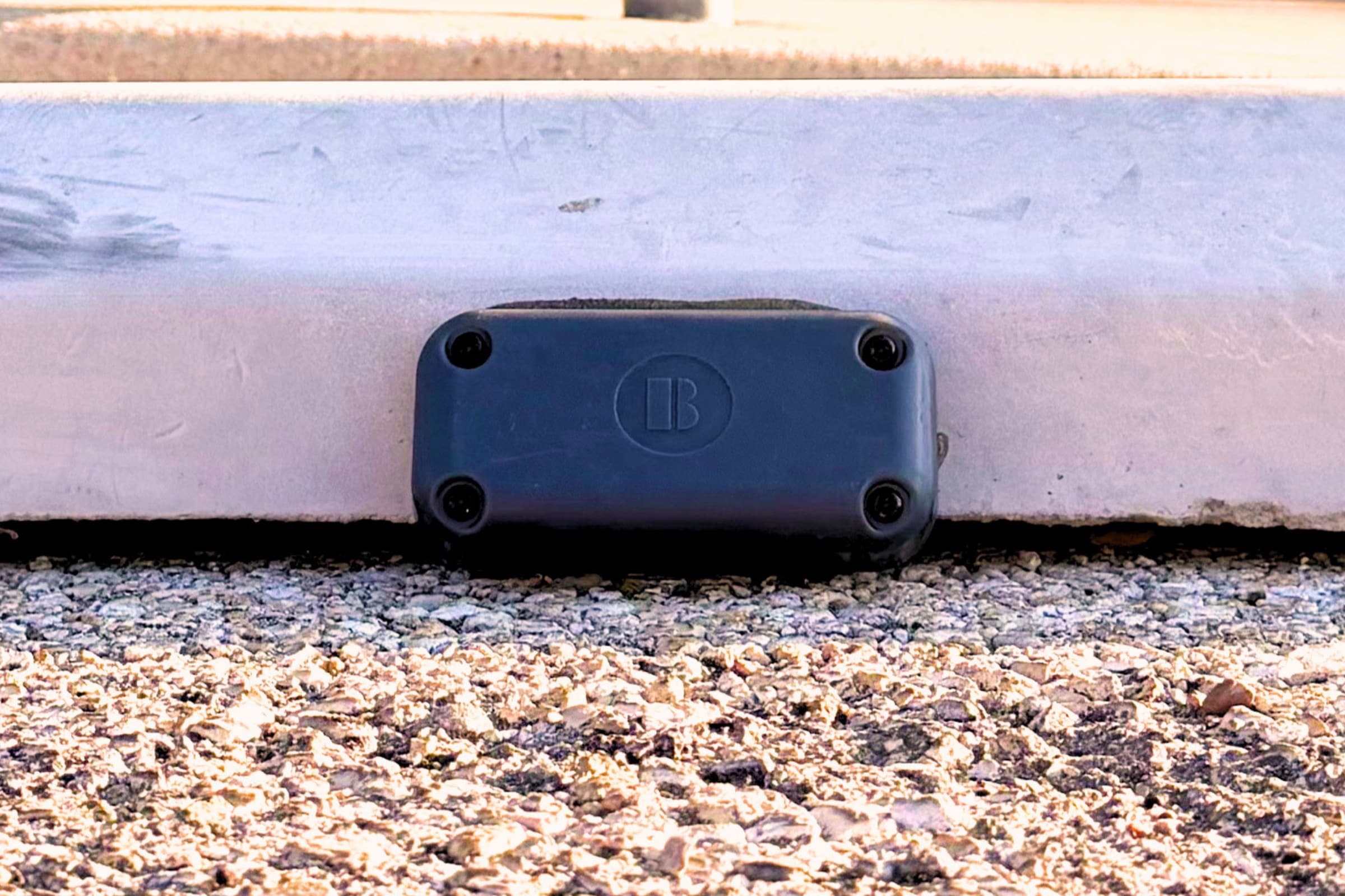 A Bizzi PS Sensor bonded to the curb face of a monitored parking space in Austin, photographed at ground level.